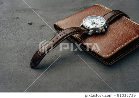 Male watch and leather wallet on dark grey surface 91033739