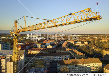 Tower crane on bright blue sky copy space background, city landscape stretching to horizon. Drone aerial photography. Tower crane on bright blue sky copy space background, city landscape stretching to horizon. Drone aerial photography. 91033763