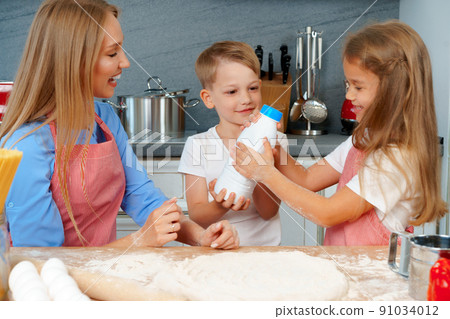 Young mother and her cute kids cooking pizza together 91034012