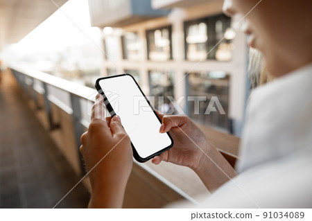 Businesswoman using her mobile phone in the balcony 91034089