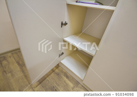 Interior of white plastic cabinet or clothing wardrobe with many empty shelves with open doors. Furniture design and installation. 91034098