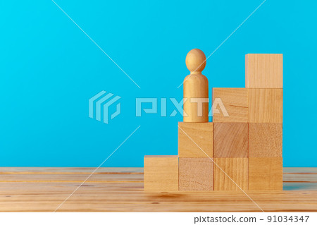 Stacked wooden blocks on wooden desk against blue background Stacked wooden blocks on wooden desk against blue background 91034347