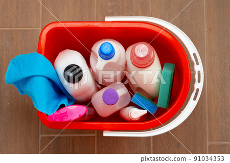 Various household cleaning detergents and bottles in a plastic bucket on the floor Various household cleaning detergents and bottles in a plastic bucket on the floor 91034353