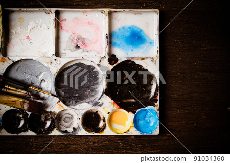 Color brushes and color mixed in white palette on wooden table Color brushes and color mixed in white palette on wooden table 91034360