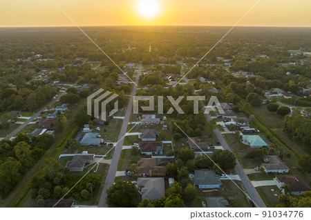 Aerial landscape view of suburban private houses between green palm trees in Florida quiet rural area at sunset 91034776