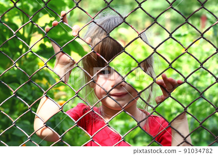 Abstract picture of a little girl behind chain link fence. Photo combination concept 91034782