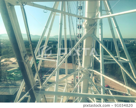 Ferris wheel. white metal beams. a huge reliable design, a carousel in the park for children. metal rods painted white 91034820