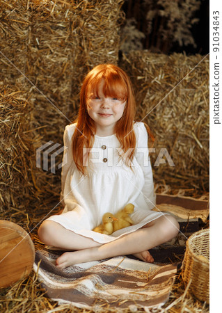 Little girl and cute ducklings are sitting in a basket in the kitchen. Little girl and cute ducklings are sitting in a basket in the kitchen. 91034843