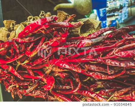 hot, red peppers are dried and hang on the counter. texture with food. pepper with seeds of a small, sharp shape. pepper with green tail 91034845
