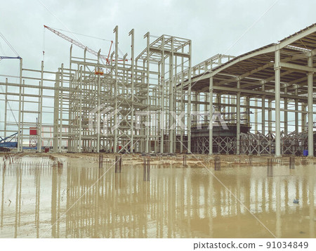 construction of a new complex at the plant. metal structures for the construction of the foundation. metal structures in rust lie in a puddle of water 91034849