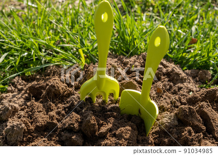 Shovel and rake in the ground. A bed in the garden. Spring, summer time. Cultivation of the land 91034985