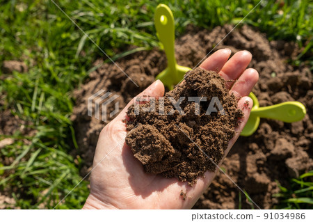 Close-up. A woman's hand holds a handful of earth. Spring, earth care Close-up. A woman's hand holds a handful of earth. Spring, earth care 91034986