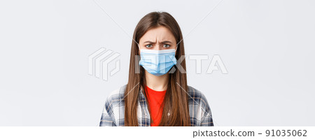 Coronavirus outbreak, leisure on quarantine, social distancing and emotions concept. Close-up of bothered or displeased woman in medical mask, condemn someone, frowning upset 91035062