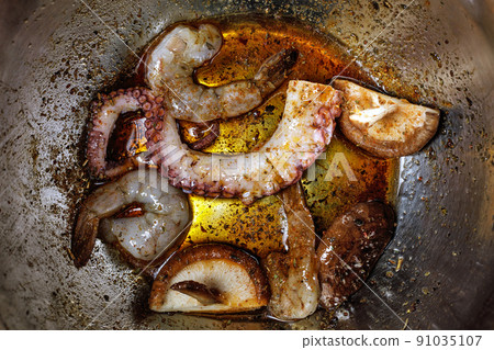 Raw seafood being marinated in metal mixing bowl. Seafood ready for grilling Raw seafood being marinated in metal mixing bowl. Seafood ready for grilling 91035107