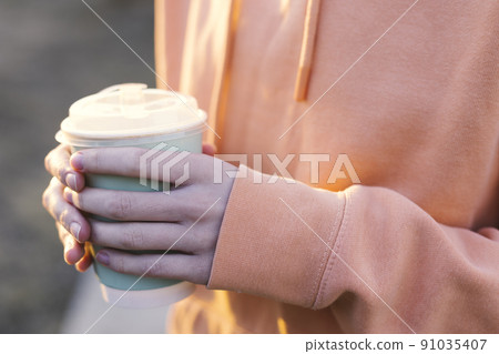 girl holding glasses of coffee in the sunset light 91035407