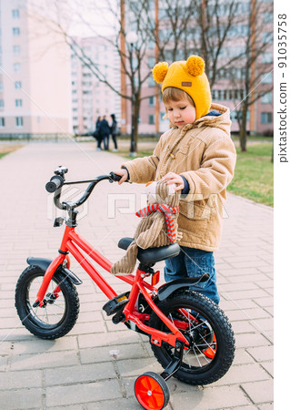 A small child learns to ride a bike for the first time in the city in spring 91035758