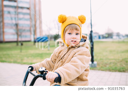 A small child learns to ride a bike for the first time in the city in spring 91035763