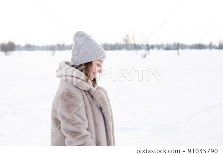 Young girl in beige clothes, fur coat made of artificial fur walks in winter Young girl in beige clothes, fur coat made of artificial fur walks in winter 91035790