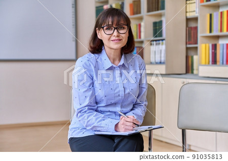 Woman teacher, counselor looking at camera in library class Woman teacher, counselor looking at camera in library class 91035813