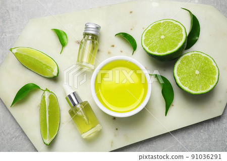Lime essential oil and cut citrus fruits on light grey table, top view Lime essential oil and cut citrus fruits on light grey table, top view 91036291