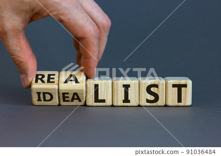 Idealist or realist. Male hand flips wooden cubes and changes the word 'idealist' to 'realist' or vice versa. Beautiful grey background, copy space. Idealist or realist concept. Idealist or realist. Male hand flips wooden cubes and changes the word 'idealist' to 'realist' or vice versa. Beautiful grey background, copy space. Idealist or realist concept. 91036484