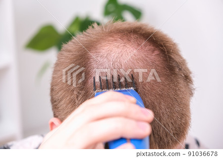 A man cuts his hair with clipper. Cutting a short A man cuts his hair with clipper. Cutting a short 91036678
