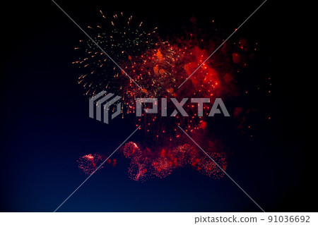 Red and orange fireworks with green sparks inside and smoke, below you can see small fireworks against the night sky. High quality photo Red and orange fireworks with green sparks inside and smoke, below you can see small fireworks against the night sky. High quality photo 91036692