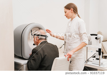 oculist examination of elderly man on device perimeter of field of view 91037119