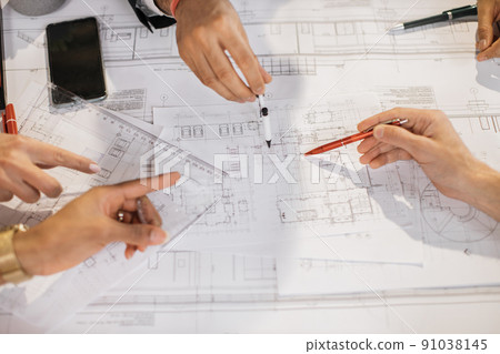 Close up of architects, engineers and designers sitting together at table and analysing blueprints. Close up of architects, engineers and designers sitting together at table and analysing blueprints. 91038145