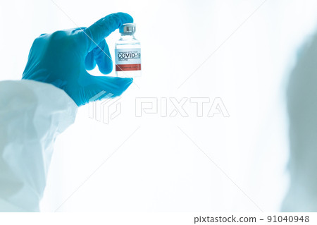 Unrecognizable specialist doctor in a medical PPE suit showing a coronavirus SARS 2019-nCoV or COVID-19 mRNA vaccine. Personal Protection Equipment or PPE suit use for coronavirus - COVID-19 pandemic. Unrecognizable specialist doctor in a medical PPE suit showing a coronavirus SARS 2019-nCoV or COVID-19 mRNA vaccine. Personal Protection Equipment or PPE suit use for coronavirus - COVID-19 pandemic. 91040948