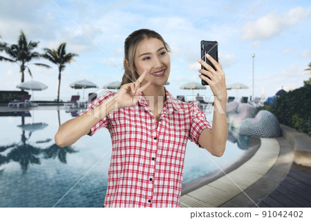 Woman tourist making selfie at swimming pool near beach. 91042402