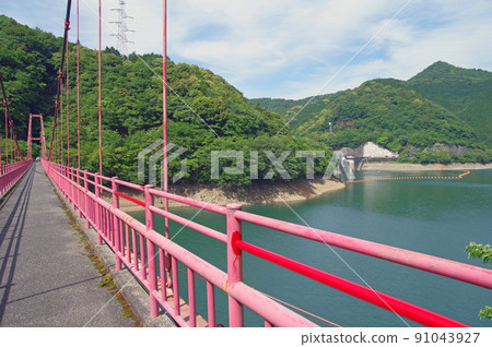 A red suspension bridge over Lake Masubuchi Dam in Kokuraminami Ward, Fukuoka Prefecture 91043927