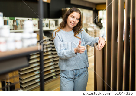Young woman buying flooring in hardware store 91044330