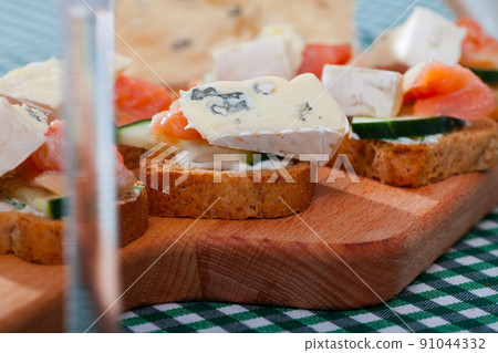 Toasted bread slices with salmon and cambozola 91044332