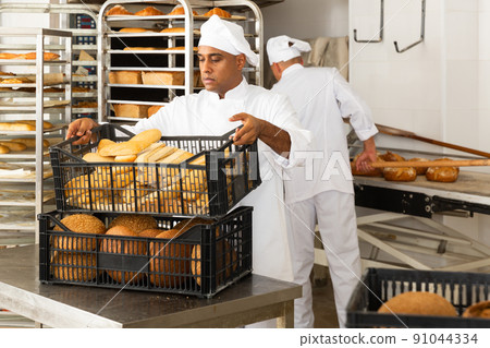 Male baker holding crate with baked bread Male baker holding crate with baked bread 91044334