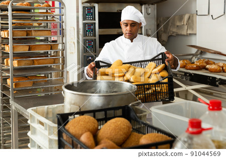 Male baker holding crate with baked bread 91044569