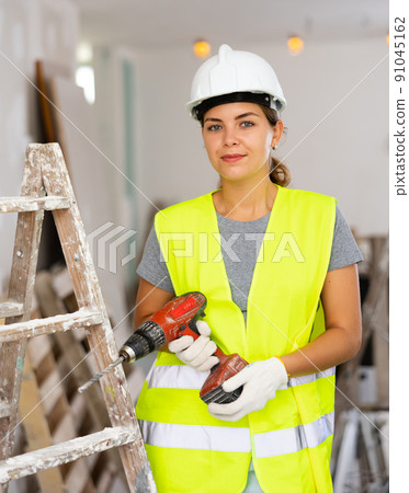 Portrait of smiling young woman repairer with drill 91045162
