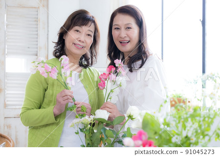 Women's lifestyle Senior women enjoying flower arrangements 91045273