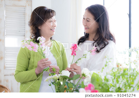 Women's lifestyle Senior women enjoying flower arrangements 91045274