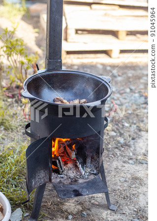Cooking food or pilaf in a cauldron on fire. Cooking in cauldron on open fire in nature. Bowler on bonfire in forest. Close-up fire flame. Copy space. 91045964
