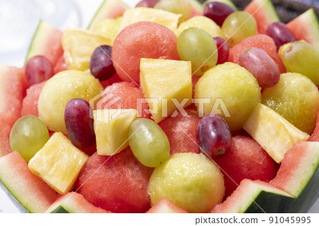 Assorted heaps of fruit with hollowed out watermelon skin 91045995