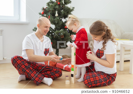 Toddler child with cochlear implant plays with parents under christmas tree - deafness and innovating medical technologies for hearing aid and diversity Toddler child with cochlear implant plays with parents under christmas tree - deafness and innovating medical technologies for hearing aid and diversity 91046652