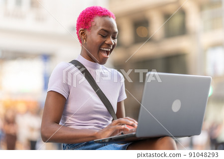 Happy african woman using the laptop on the street 91048293