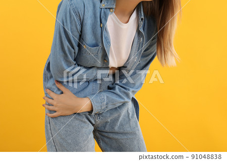Girl with abdominal pain on yellow background Girl with abdominal pain on yellow background 91048838