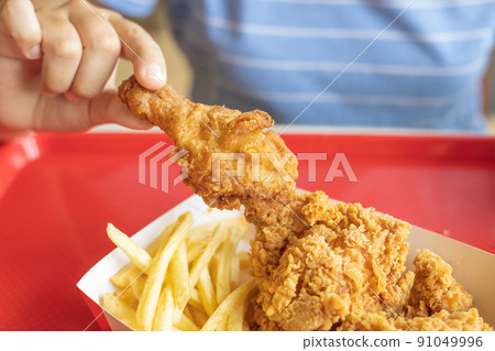 closeup people eating fried chicken with potato stick french fries American style fatty food. 91049996