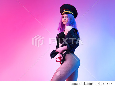 Sexy girl in police uniform posing in underwear with handcuffs in neon light 91050327