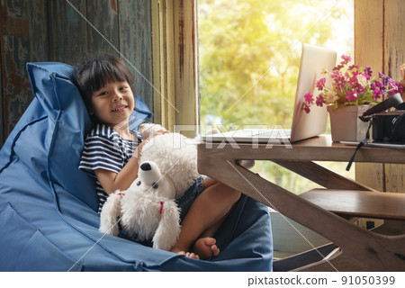 Cute Little asian Girl Sitting use Laptop at the Desk in the Living Room 91050399
