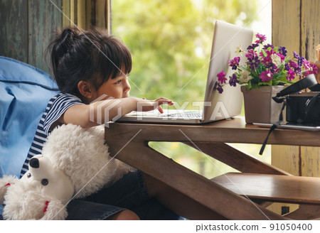 Cute Little asian Girl Sitting use Laptop at the Desk in the Living Room Cute Little asian Girl Sitting use Laptop at the Desk in the Living Room 91050400