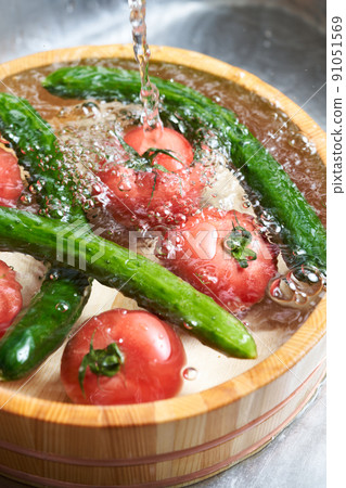 Wash the cucumbers and tomatoes in a tub Wash the cucumbers and tomatoes in a tub 91051569
