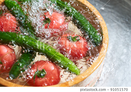 Wash the cucumbers and tomatoes in a tub Wash the cucumbers and tomatoes in a tub 91051570